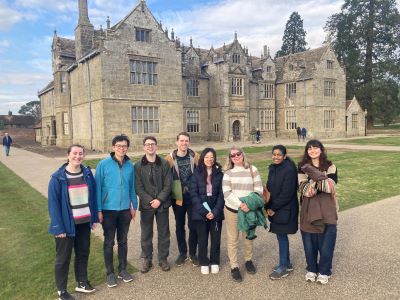 A group of visitors pose in front of a sixteenth century Manor House at Wakehurst